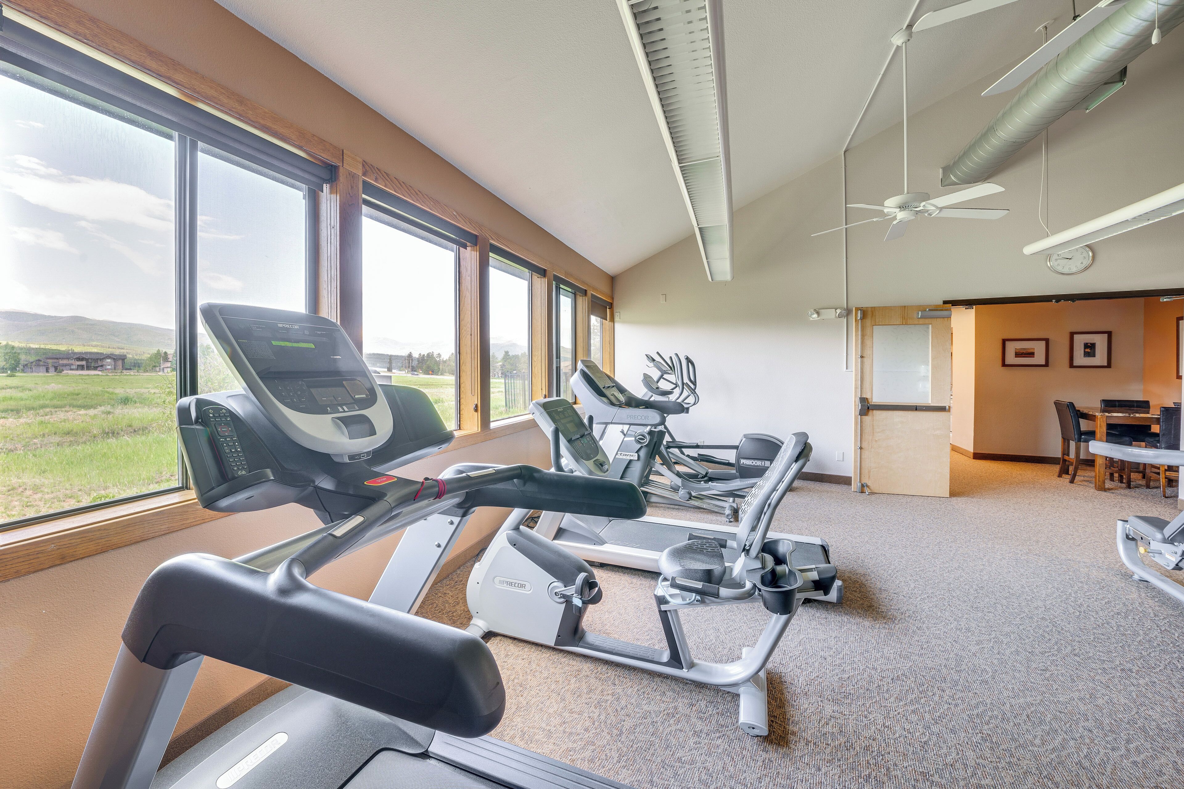 A gym with treadmills, stationary bikes, and a ceiling fan.