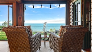 Una cabaña de madera con muebles de mimbre y vista al océano.