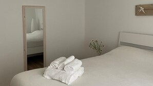 A bedroom with a bed, a mirror, an air conditioner, and a wall-mounted bird sculpture.