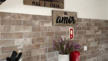 A kitchen with a brick backsplash, a wooden sign above the sink, a potted plant, a candle, and a fire extinguisher.