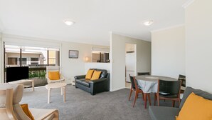 A modern living room with a sofa, armchair, and dining table.
