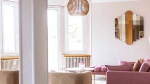 A living room with a sofa, a coffee table, and a hanging light fixture. - Le Cashmere - au centre de tout (Annecy)