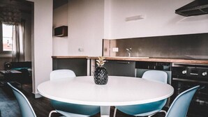 A modern kitchen with a round dining table and blue chairs, a wooden countertop, and a built-in oven.
