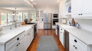 A spacious kitchen with white cabinetry, stainless steel appliances, and a large window providing natural light. - Minutes from Downtown St. Michaels | Pool | Outdoor Kitchen | Private Dock | Hot (Easton)