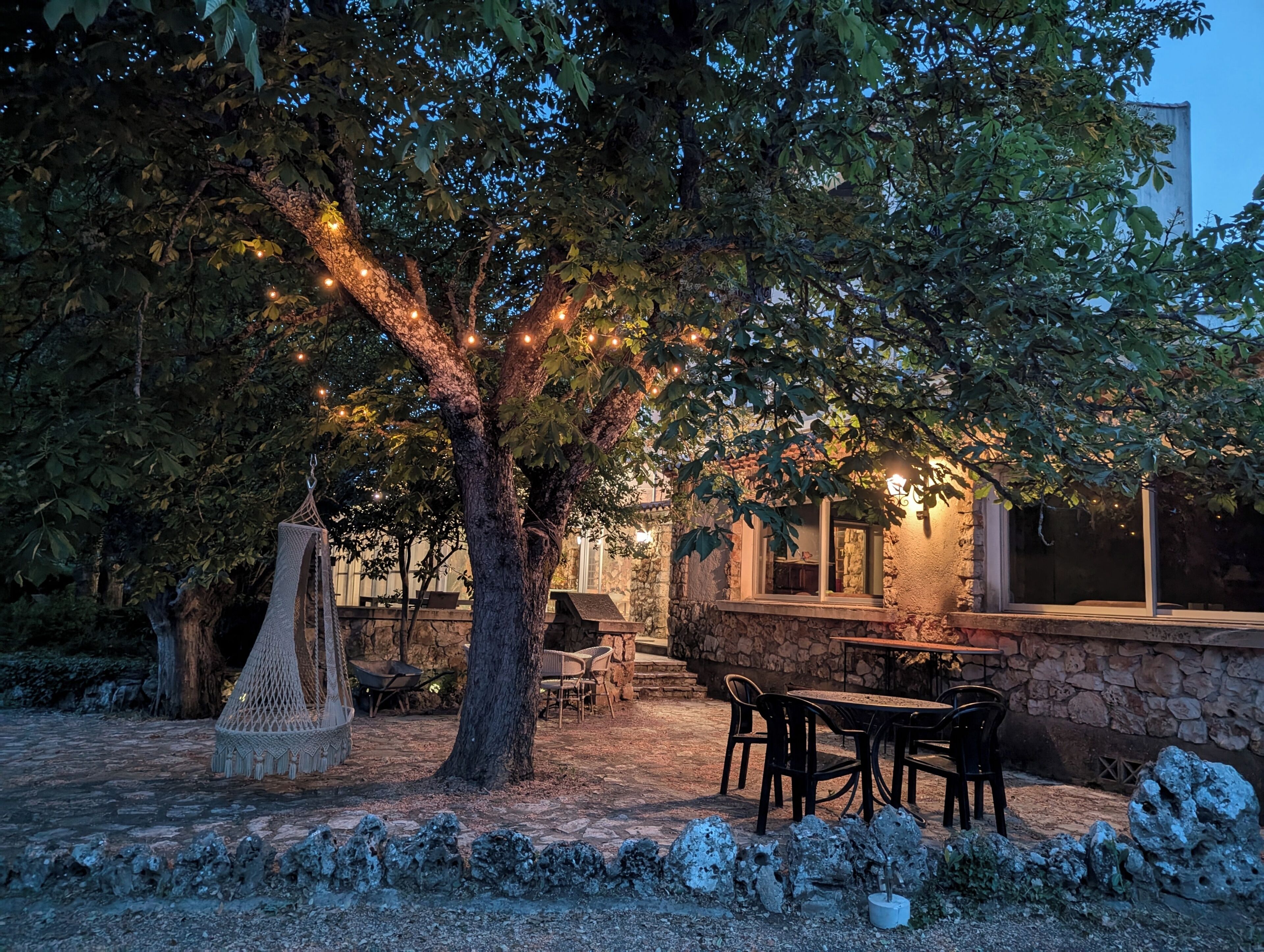 A stone building with outdoor seating and string lights.