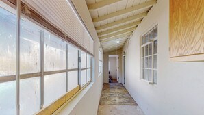 A narrow hallway with large windows on one side and a door at the end.