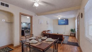 A dining area with a table set for four, a sofa, and a TV mounted on the wall.