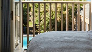 A bedroom with a large bed, a balcony with a view of the sea, and a sliding glass door. - Beachfront House w Pool Steam (Chichester)
