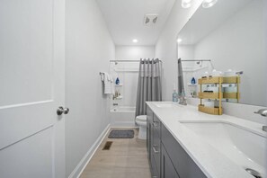A narrow bathroom with a white sink, a mirror, and a shower curtain. - Downtown Wake Forest Luxury Condo | Rooftop Terrace + EV Charger (Wake Forest)