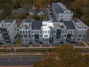 A modern apartment building with multiple units, a parking lot, and a street view. - Downtown Wake Forest Luxury Condo | Rooftop Terrace + EV Charger (Wake Forest)