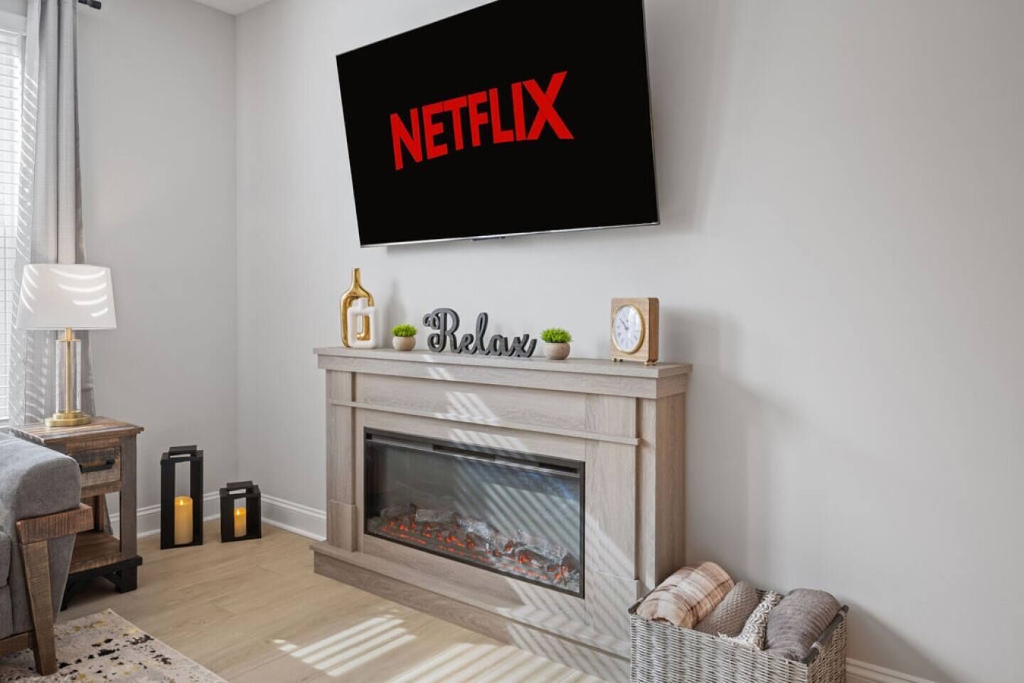 A living room with a fireplace, a mounted TV displaying 'NETFLIX', and a 'Relax' sign above it.