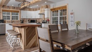 A modern kitchen with wooden accents, white cabinets, and a central island with bar stools. - Boone Getaway | Dog Friendly, Hot Tub, Fire Pit! (Watauga County)