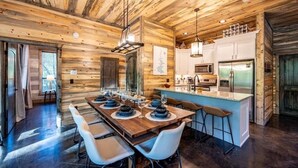 A modern log cabin interior with a dining area, kitchen, and bar. - Island in the Stream Spacious Creekside Cabin - Wi-Fi, Hot Tub, Arcade (Broken Bow)