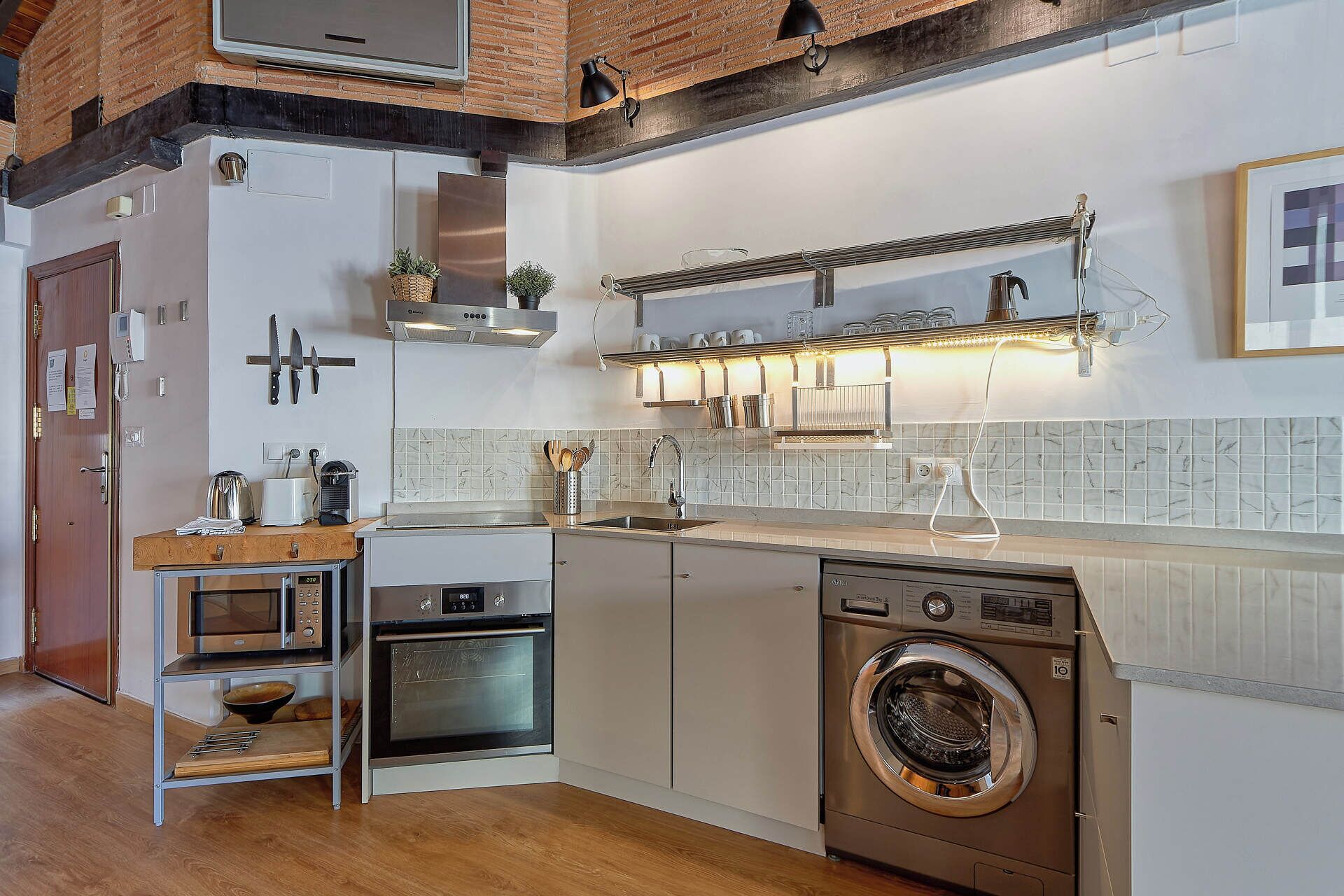 A compact kitchen with a built-in oven, a washing machine, and a microwave.