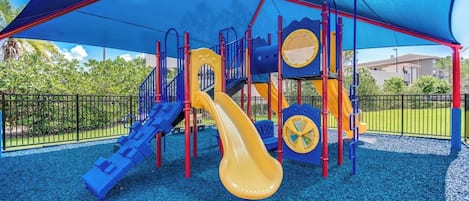 Un parque infantil con tobogán, estructuras para escalar y una zona cubierta.