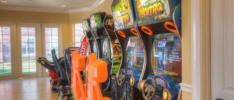 Une rangée de bornes d’arcade proposant divers jeux, dont un jeu Nicktoons Nitro, dans une pièce dotée de grandes fenêtres et d’un sol carrelé.