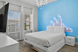Een slaapkamer met een bed, nachtkastje, televisie en een muur met silhouet van een kasteel.