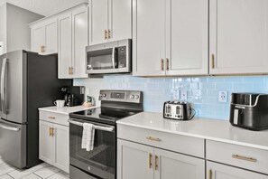 A modern kitchen with stainless steel appliances, white cabinetry, and a tiled backsplash. - Resort 4BR Home near Disney w/ Pool & Themed Rooms (Kissimmee)