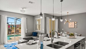 Une cuisine moderne dotée d’un grand îlot central, d’un coin repas et donnant sur une piscine.