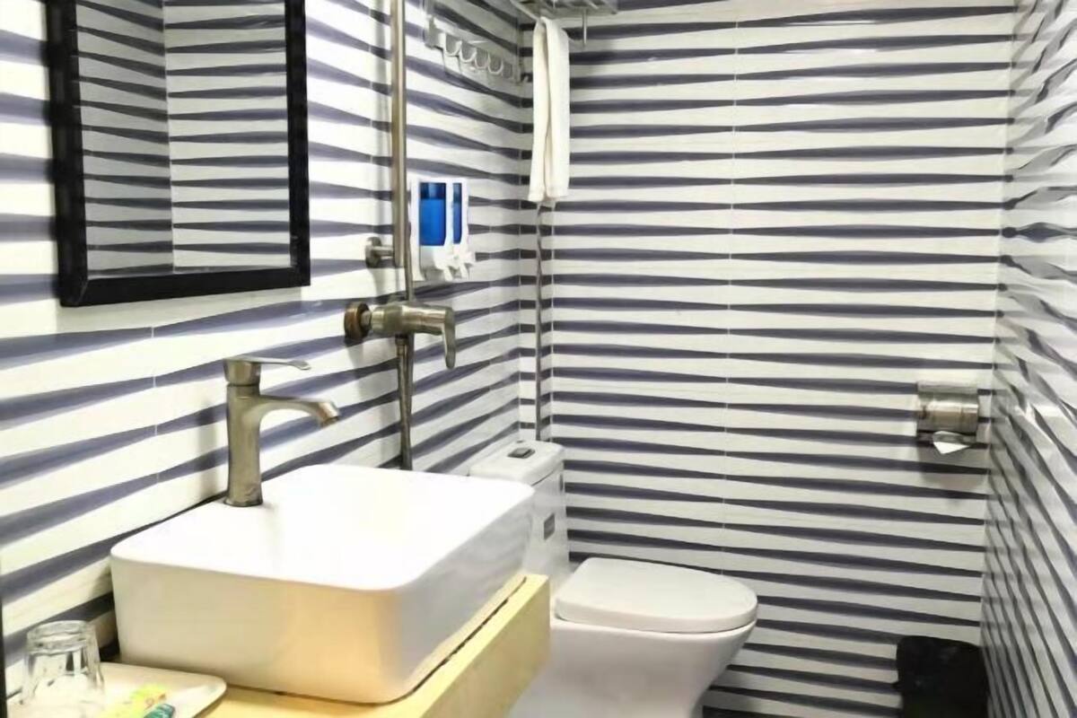 A bathroom with a striped wall pattern, a white sink, a toilet, and a mirror.