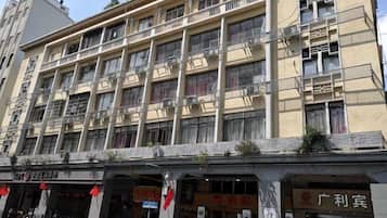 A multi-story building with balconies, air conditioning units, and storefronts with signage.