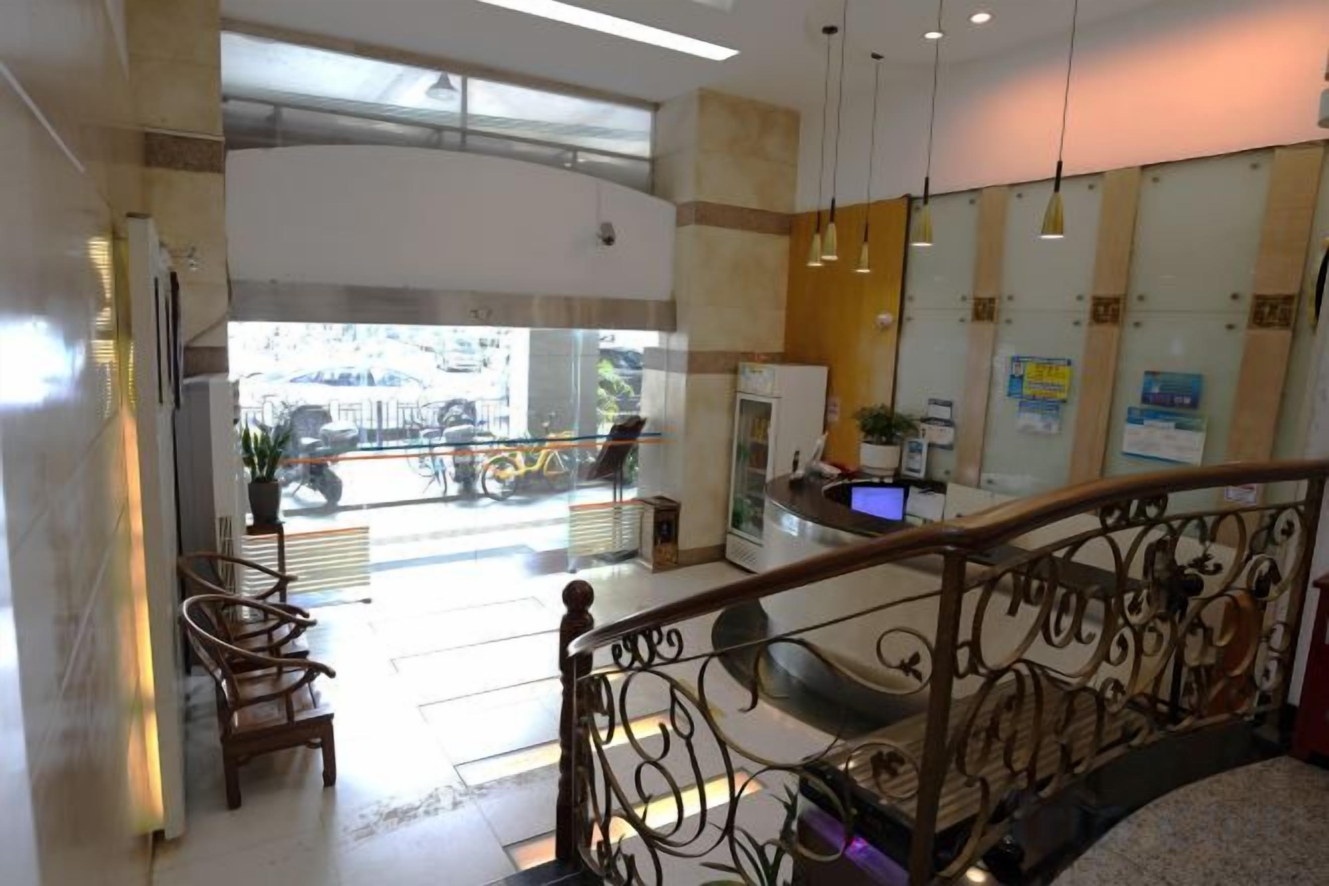 A hotel lobby with a staircase, seating area, and a reception desk.