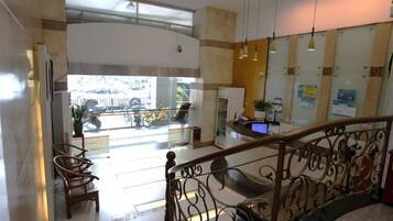 A hotel lobby with a staircase, seating area, and a reception desk.