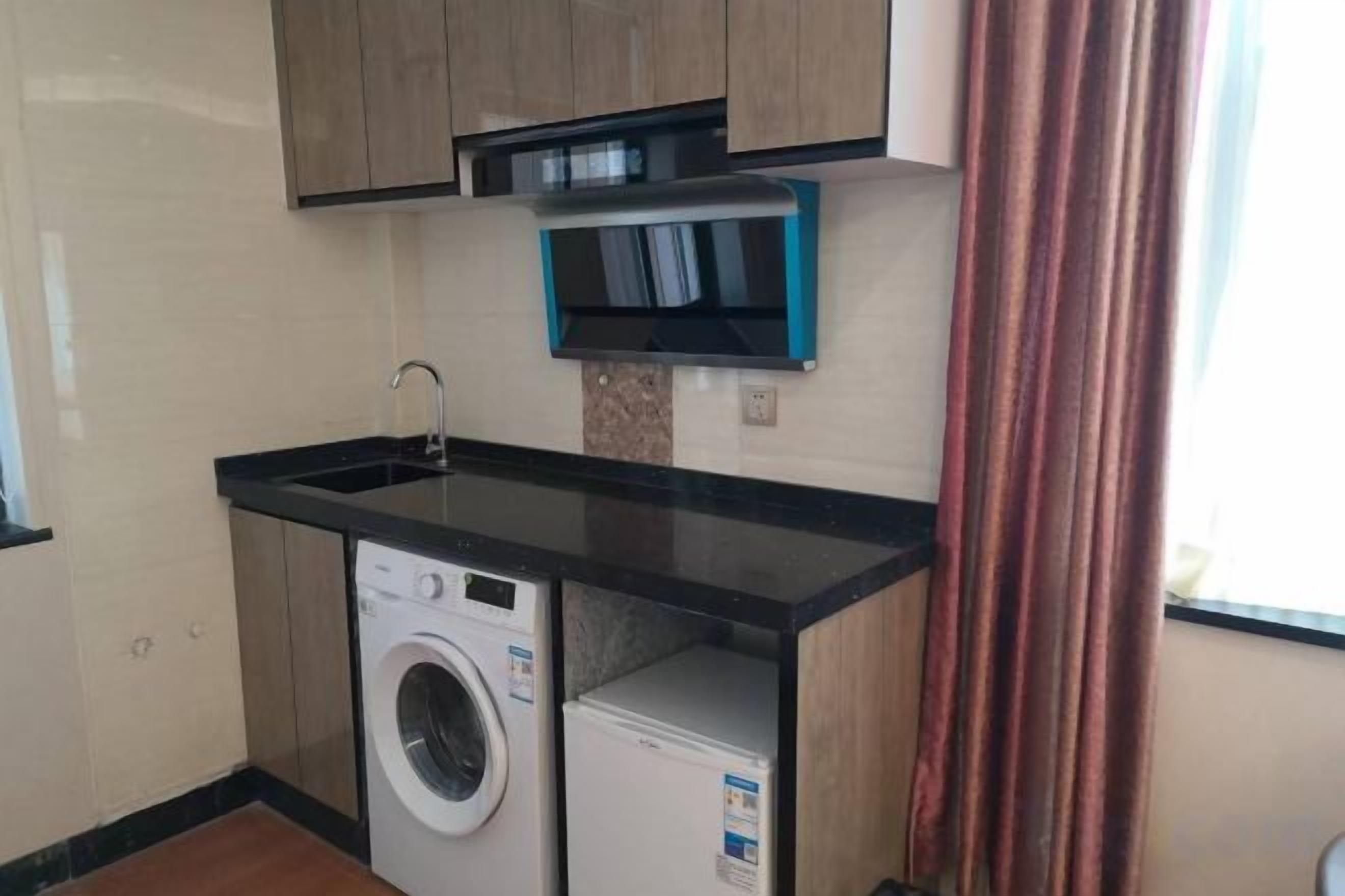 A compact kitchen with a washing machine, a sink, and a microwave.
