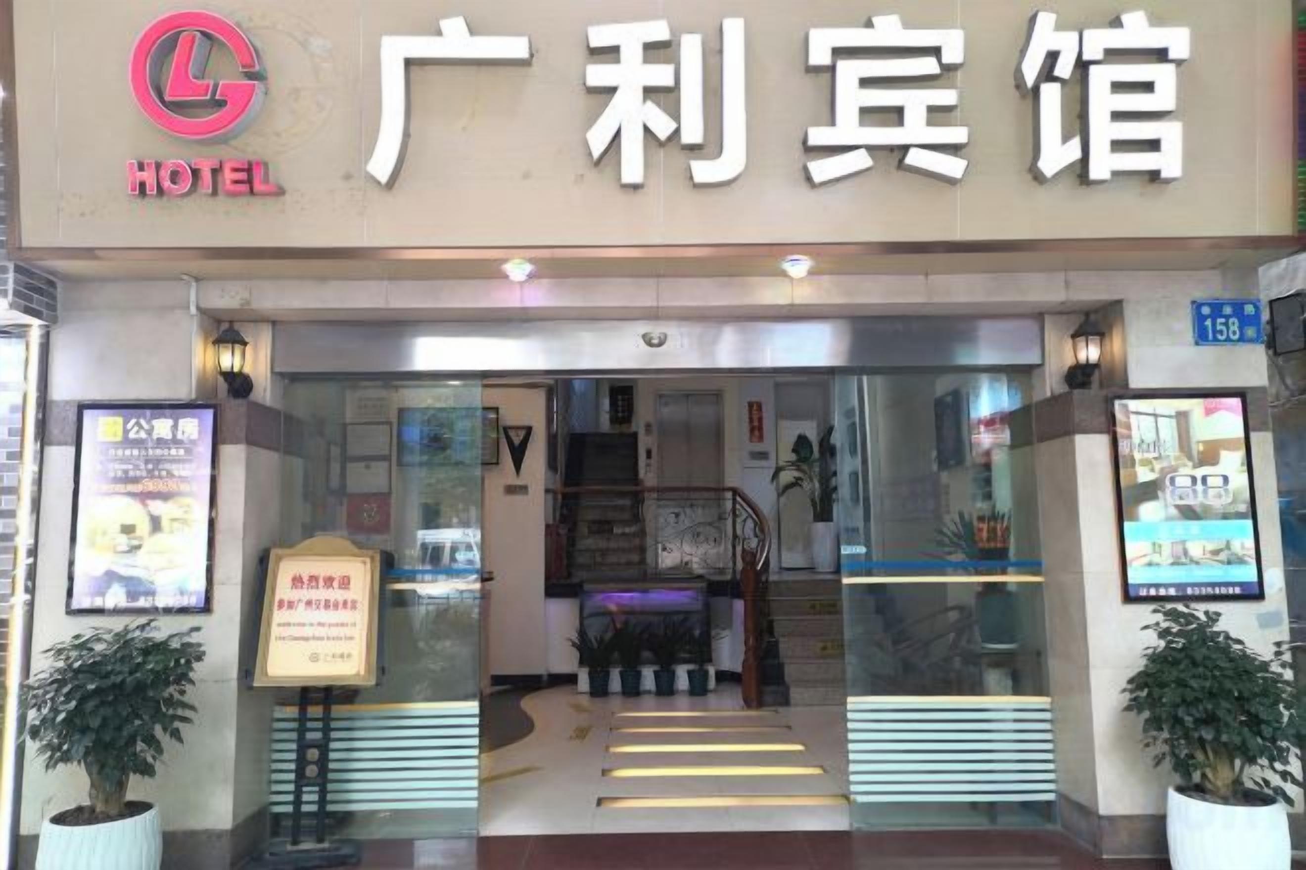 La entrada de un hotel con un cartel visible, un mostrador de recepción y una escalera que conduce al interior.