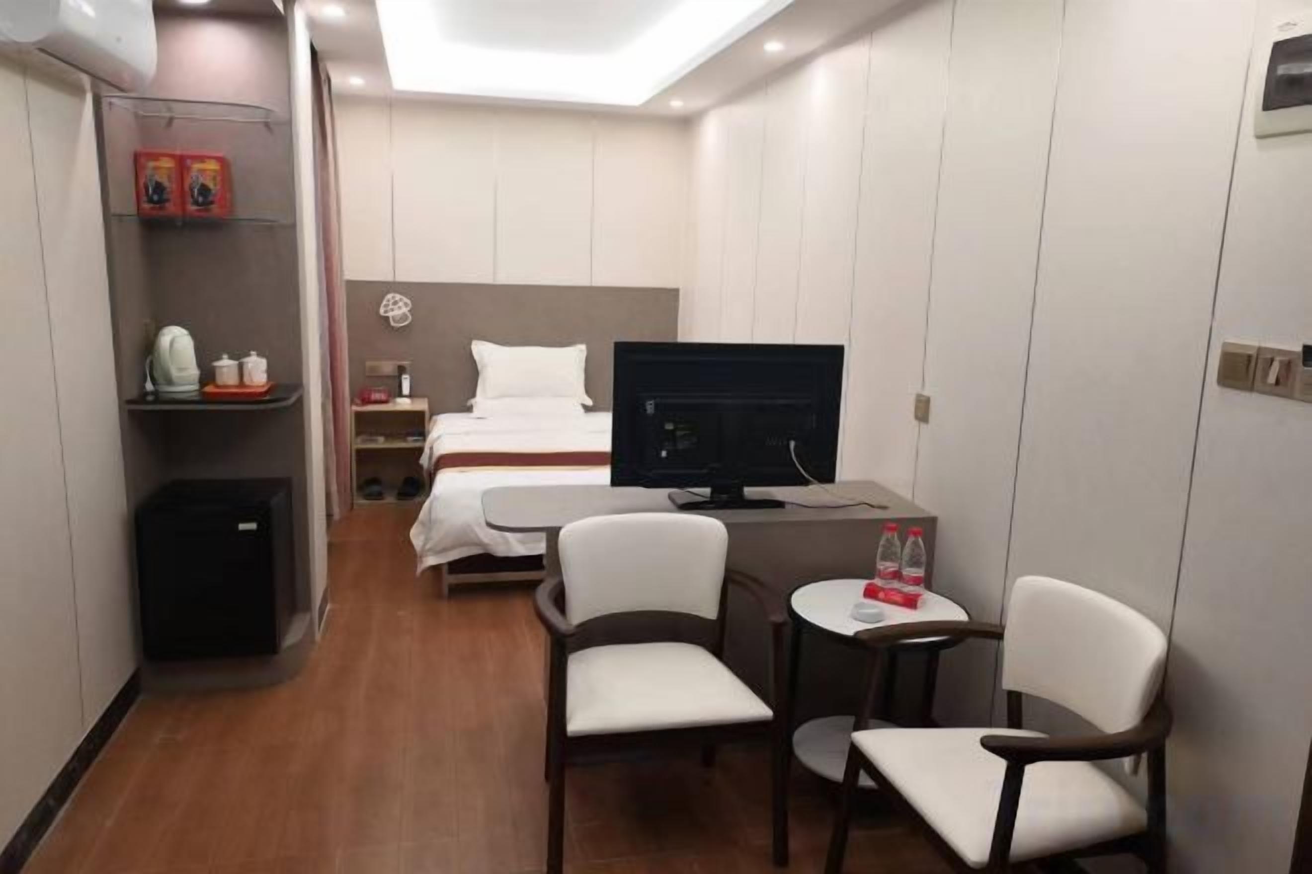 Una habitación de hotel con cama, escritorio, televisión y zona de estar.
