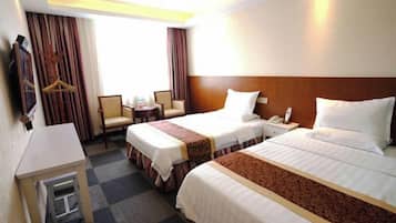 A hotel room with two beds, a desk, a chair, a small table, and a TV.