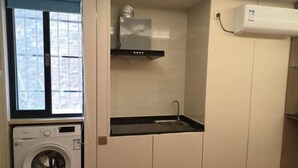 A compact laundry room with a washing machine, a small sink, and a microwave. - Guangli Hotel (Haizhu Square) (Guangzhou)
