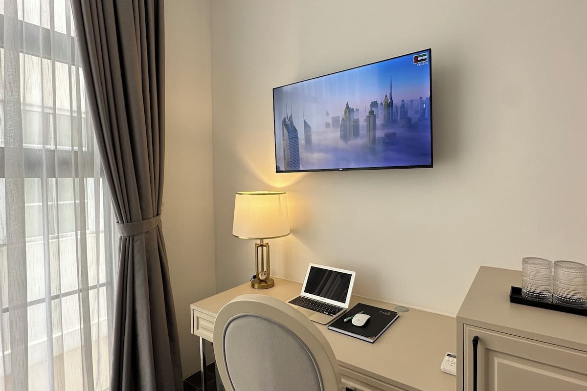 Une chambre d’hôtel équipée d’un bureau, d’un ordinateur portable, d’un téléviseur fixé au mur et d’un appareil de climatisation.