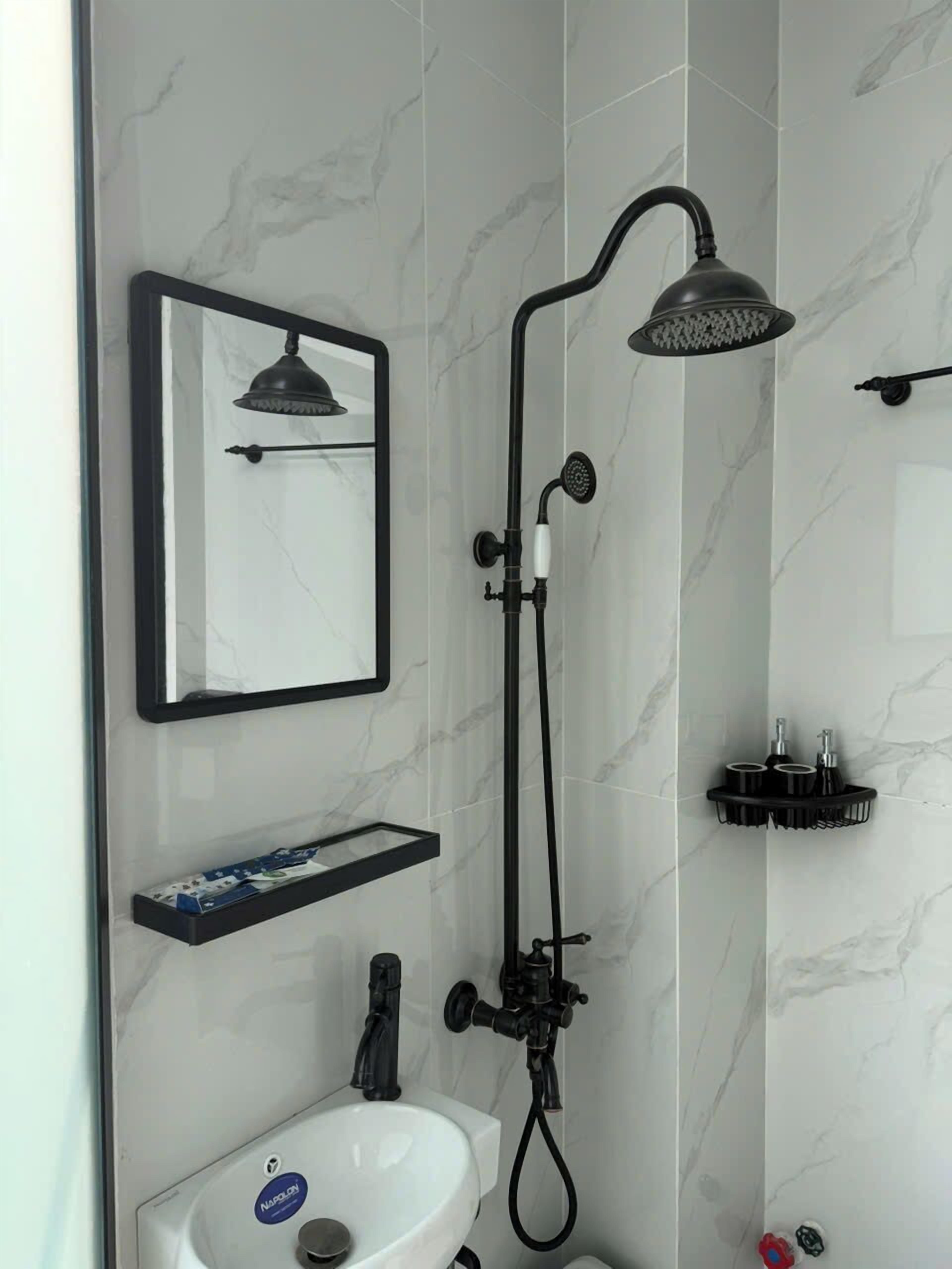 A bathroom with a shower, a sink, a mirror, and a towel rack.