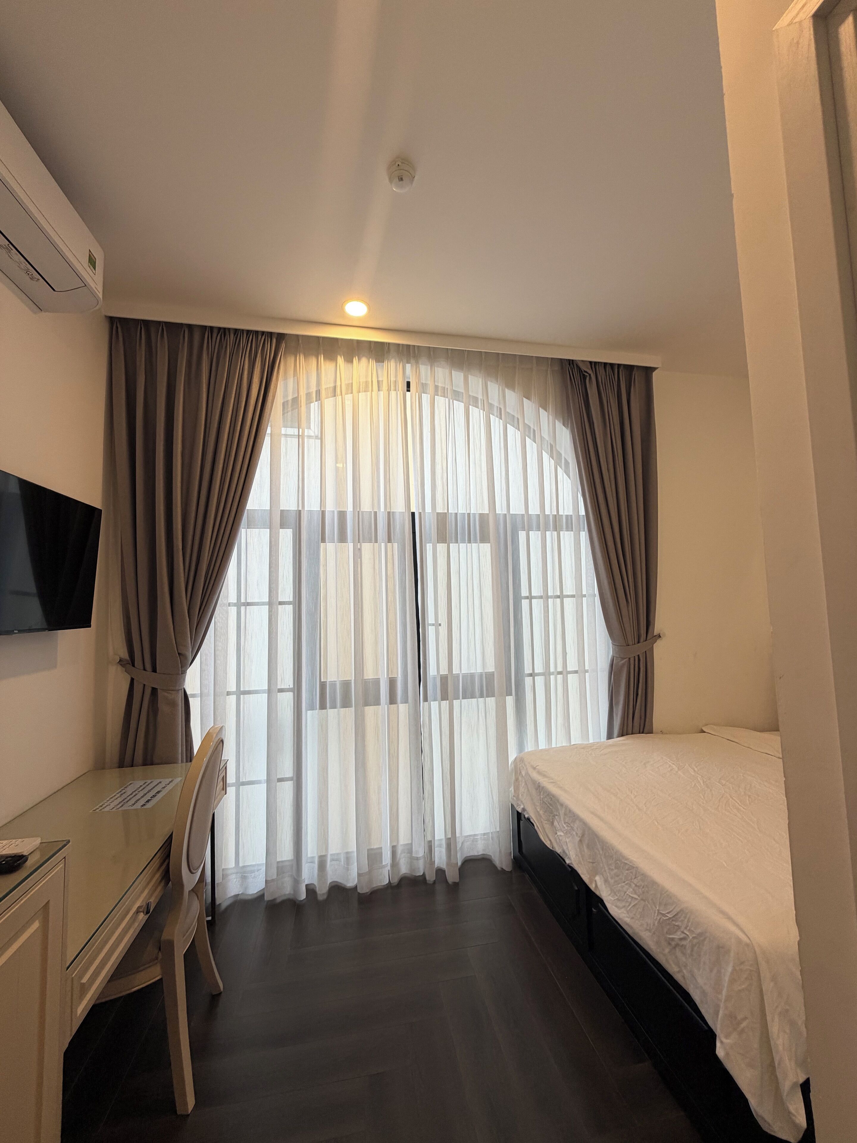 A hotel room with a bed, a desk, and a chair.