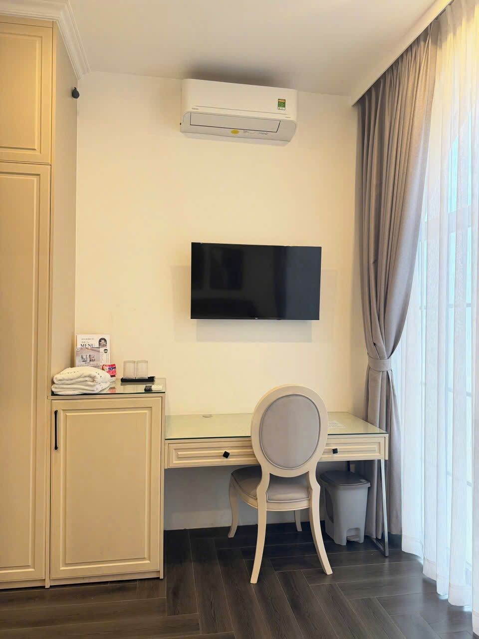 Una habitación de hotel con escritorio, silla, televisor y aire acondicionado.
