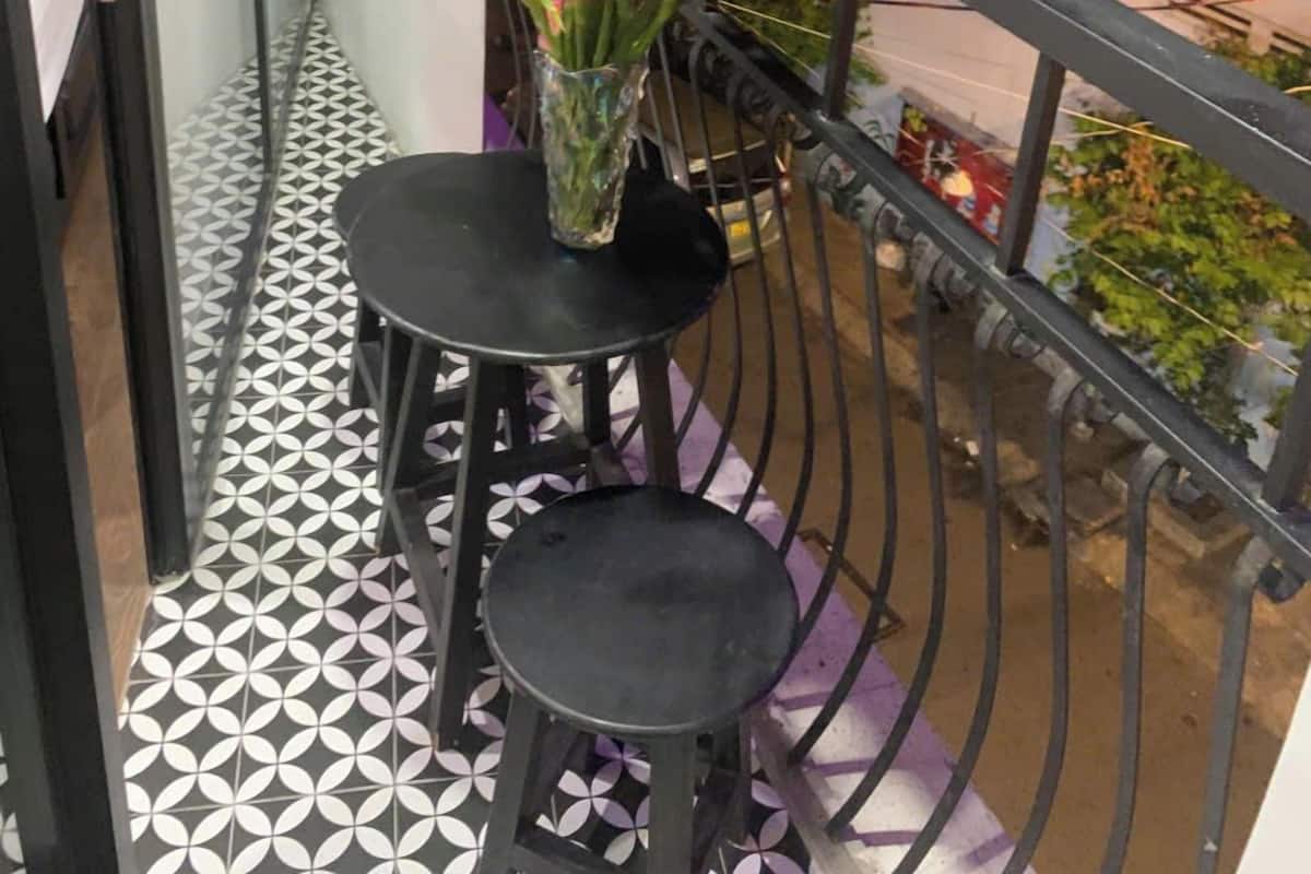 Un balcon doté d’un sol à motifs, d’une petite table et d’un vase rempli de fleurs.