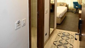 A hotel room with a bed, a desk, a chair, and a bathroom with a shower. - Tulsi Bhawan, Ayodhya (Faizabad)