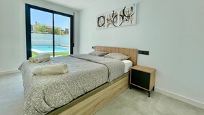 Una camera moderna con un letto grande, un comodino e vista su una piscina.