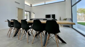 Un'area pranzo moderna con un tavolo lungo, sedie nere e una TV a schermo piatto appesa al muro.