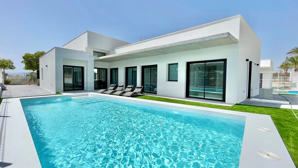 Una casa moderna con piscina, ampie finestre e un prato curato.