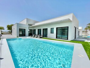 Una casa moderna con piscina, amplios ventanales y un césped bien cuidado.