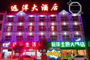 Fachada de hotel con señalización iluminada y varias ventanas.