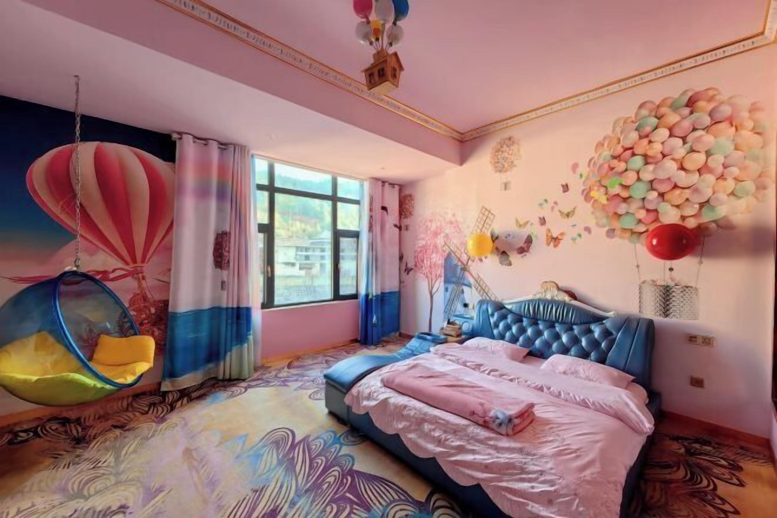 A bedroom with a large bed, a hanging chair, and a mural of a hot air balloon.