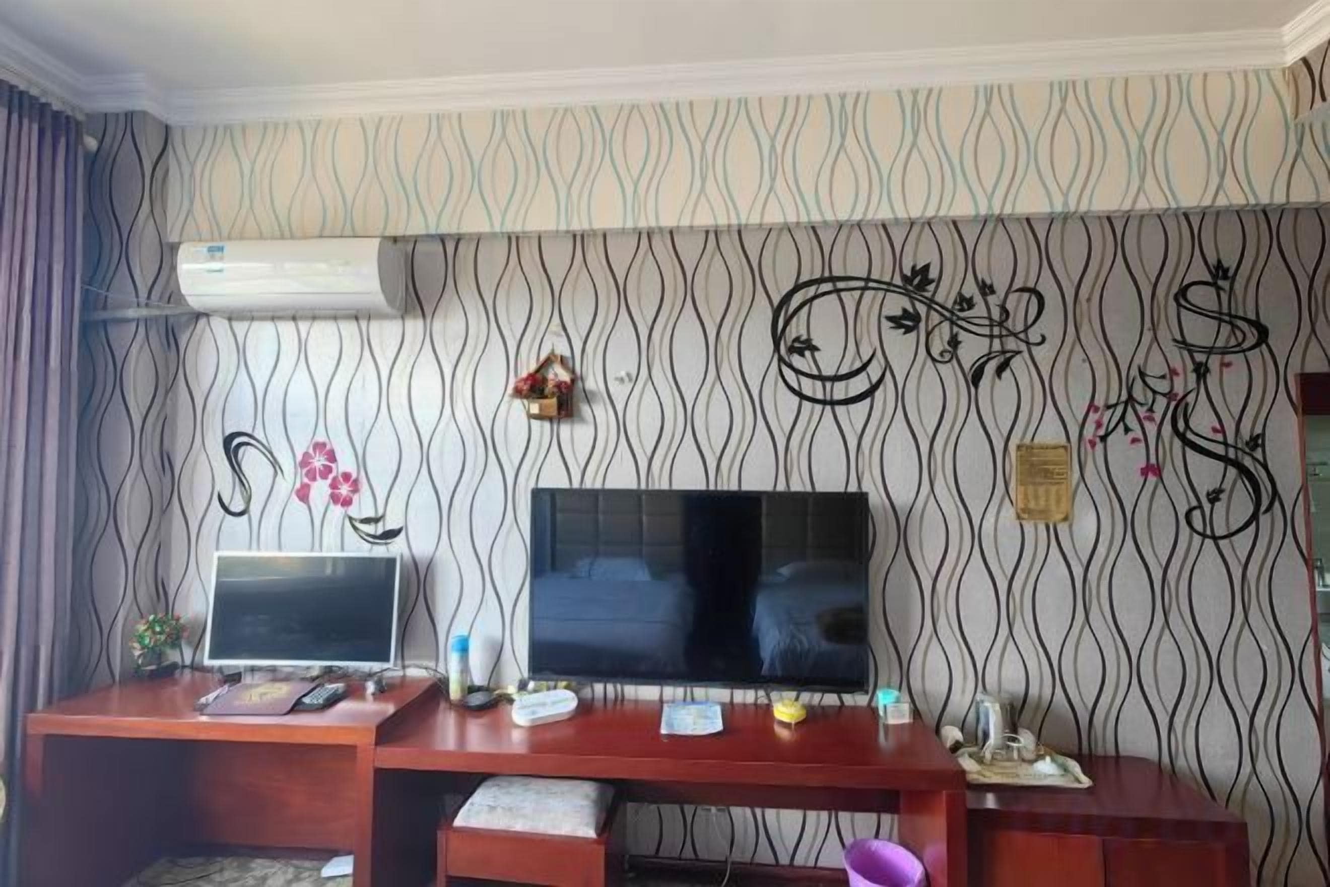A room with a television, desk, and decorative wall.