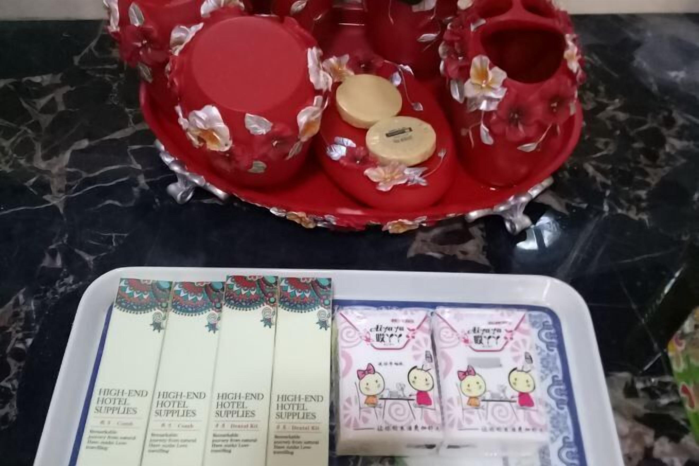 A tray with red decorative items and a box of hotel supplies.