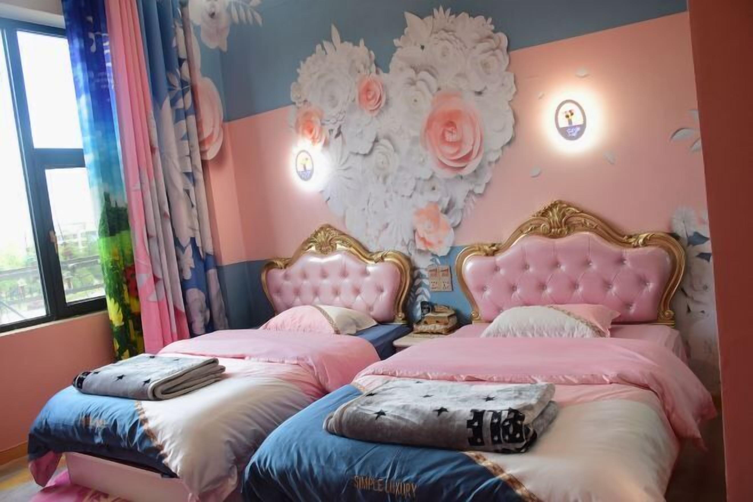 Camera da letto con due letti, ognuno con testiera rosa e biancheria da letto coordinata.