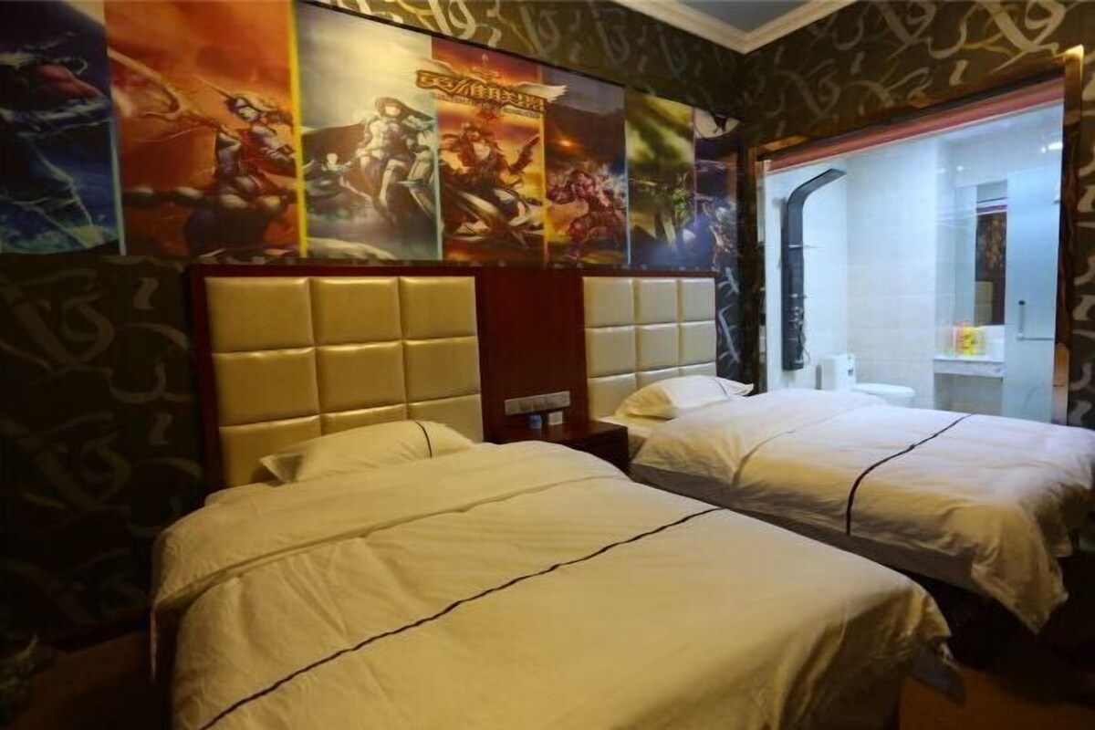 A hotel room with two beds, a headboard, and posters on the wall.