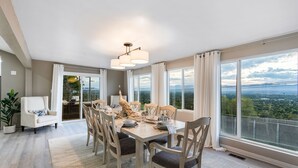 A dining area with a large table, chairs, and a view of the city through large windows.