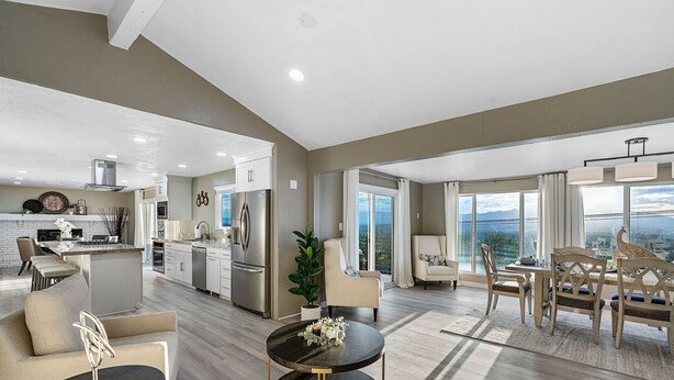 A spacious living area with a modern kitchen, dining area, and a large window offering a city view.